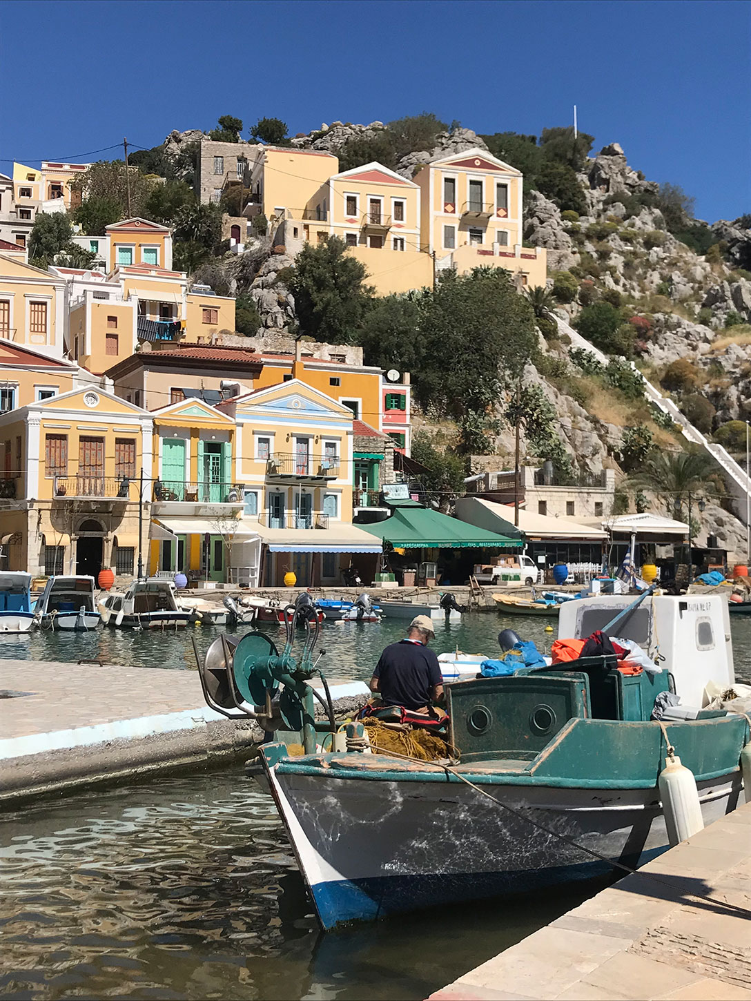 Symi fishing boat, monument in the background.