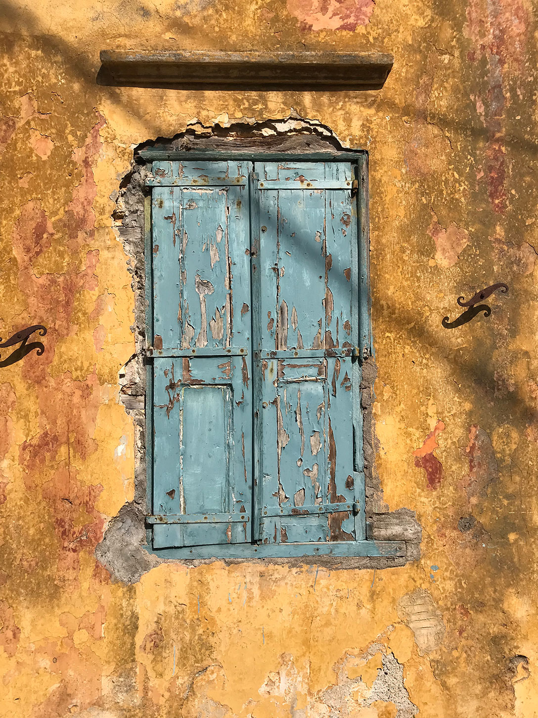 Symi Kali Strata. Amazing contrast of colors. Old wooden teal window on a golden wall.